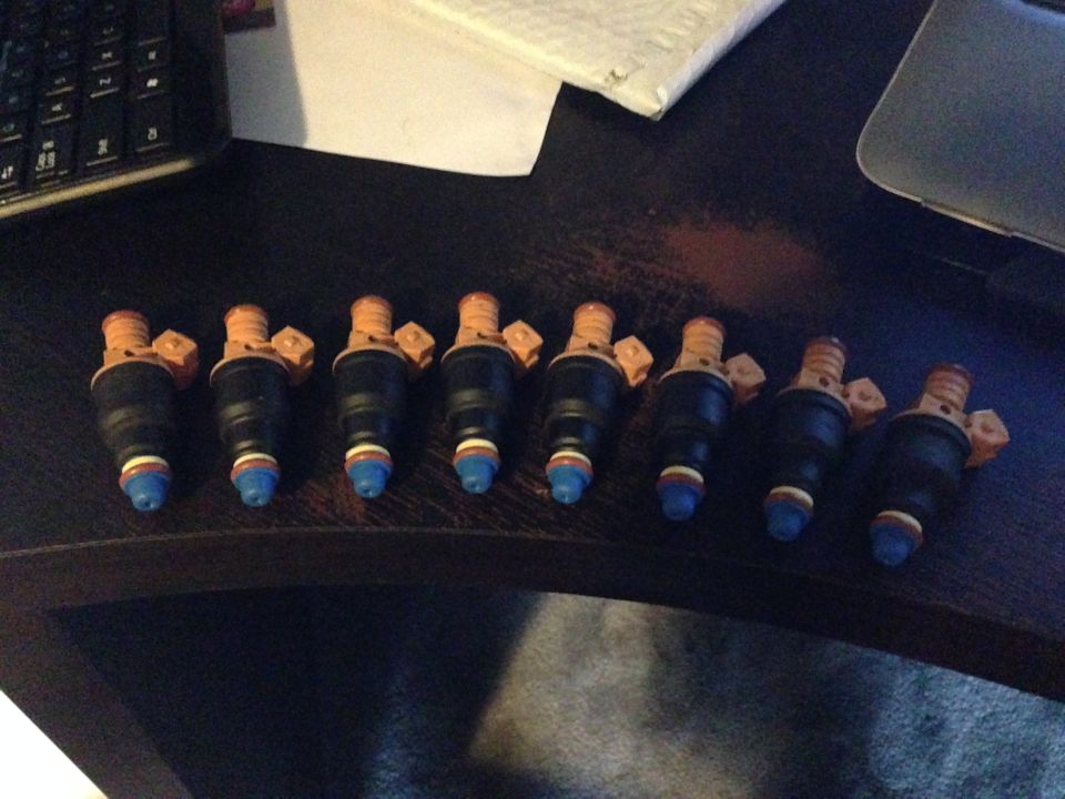 Eight black fuel injectors with orange tops and blue tips