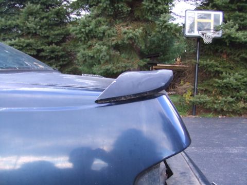 1996 Ford Bronco - A close-up of a spoiler attached to the rear of a blue vehicle, with a basketball hoop visible behind it.