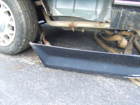 1996 Ford Bronco - A strap is attached to the frame of a vehicle, with the exhaust pipe and part of the tire visible.