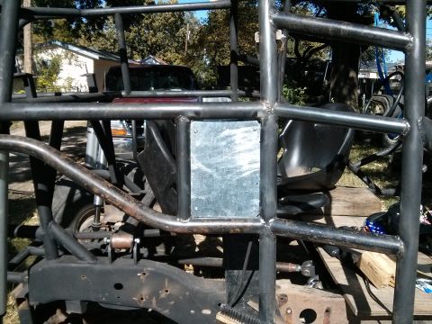 1986 Ford Bronco - Custom roll cage and vehicle frame with parts of a maroon truck visible in the background.