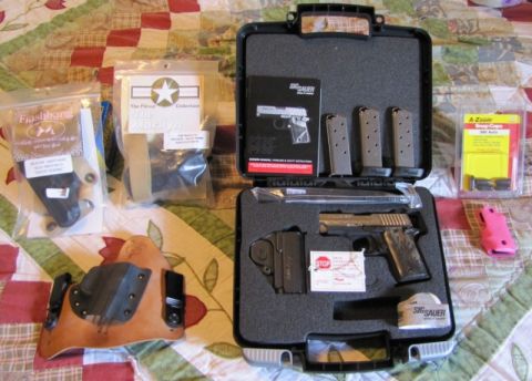 1992 Ford Bronco - A Sig Sauer pistol is displayed in its case with various accessories, including a holster and extra magazines.
