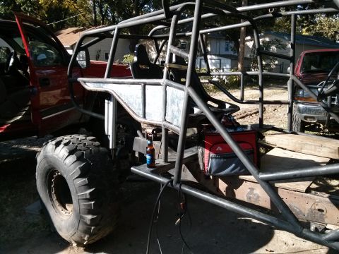 1986 Ford Bronco - A custom-built off-road vehicle is shown with a prominent roll cage and large tires, with another vehicle in the background.
