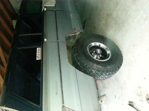 1982 Jeep Wagoneer - A Jeep Grand Wagoneer is parked indoors, showing its side profile and a spare tire mounted externally.