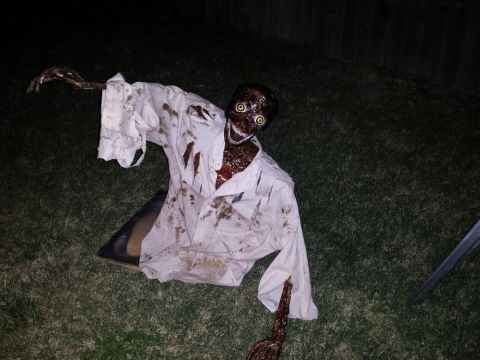 1989 Ford Bronco - Creepy zombie prop set up for Halloween, appearing to crawl out of the ground.