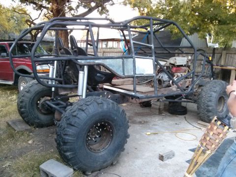 1986 Ford Bronco - A custom-built off-road buggy is shown with a roll cage and large tires, with a red pickup truck in the background.