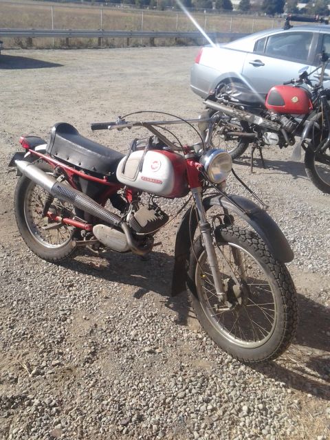 1991 Ford Bronco - Two vintage motorcycles are parked outdoors on a gravel lot.