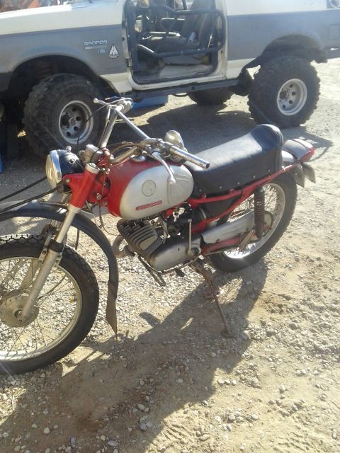 1991 Ford Bronco - A vintage motorcycle is parked in front of a modified Ford Bronco with its doors removed.