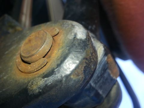 1994 Ford Bronco - This image shows a close-up view of a rusted bolt and bracket, likely from a vehicle's undercarriage.