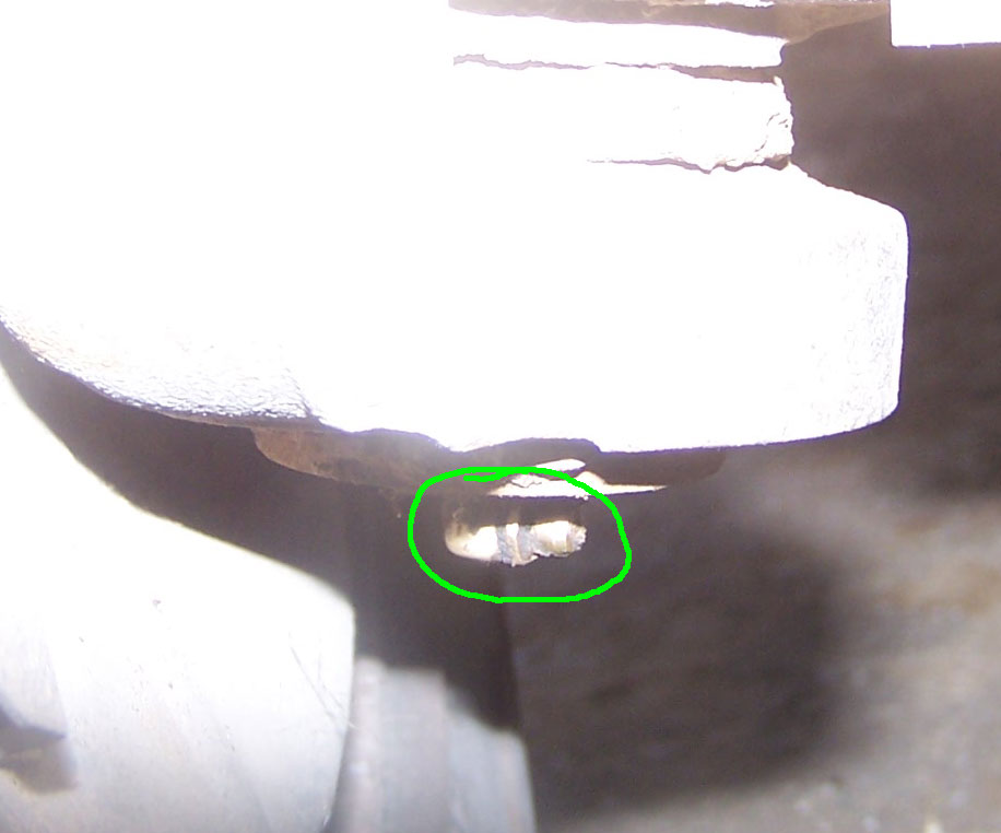 Close-up of a rusty bolt with a cotter pin on a vehicle component.