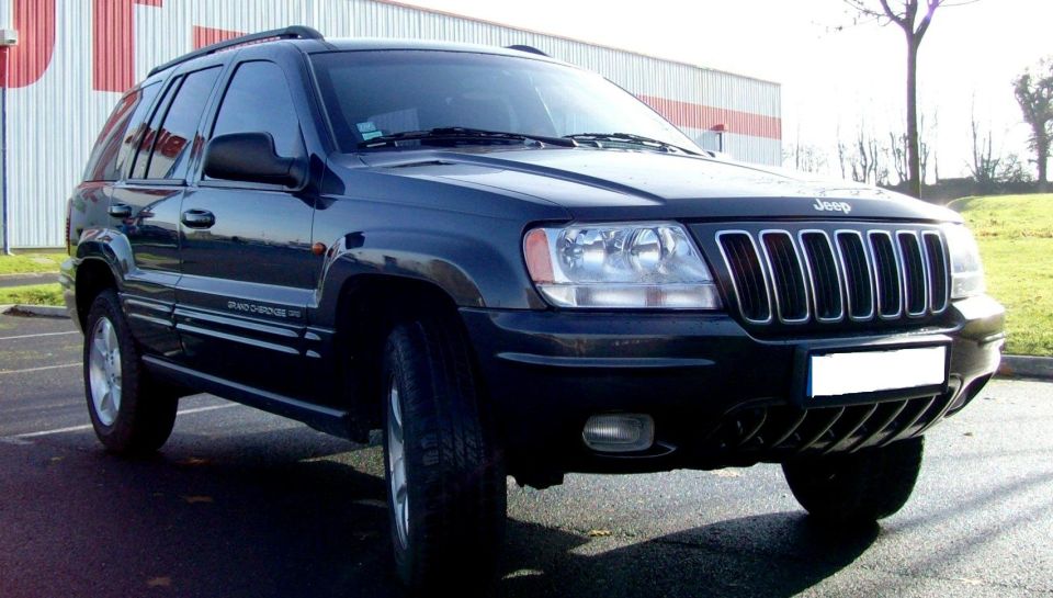 Dark blue Jeep Grand Cherokee parked outside a warehouse, front three-quarter view