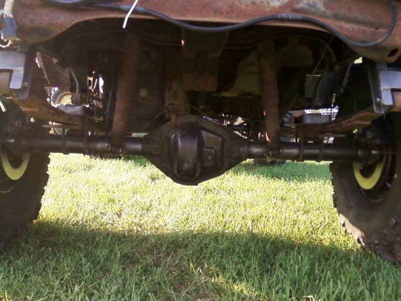 Underside of a vehicle showing rear axle, leaf springs, and shocks.
