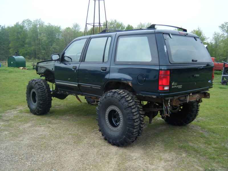 Lifted 1993 Ford Explorer SUV with oversized off-road tires, no front fender or bumper.