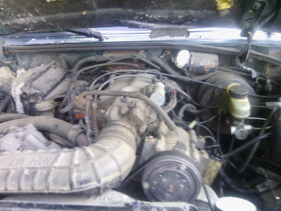 Engine bay of a 1993 Ford Explorer, showing air intake, engine parts, hoses, and wires.