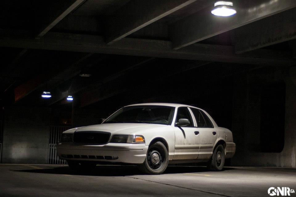 White 2006 Ford Crown Victoria sedan parked in a dark concrete structure.