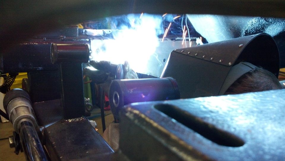 Welder working on metal parts with bright sparks and smoke.
