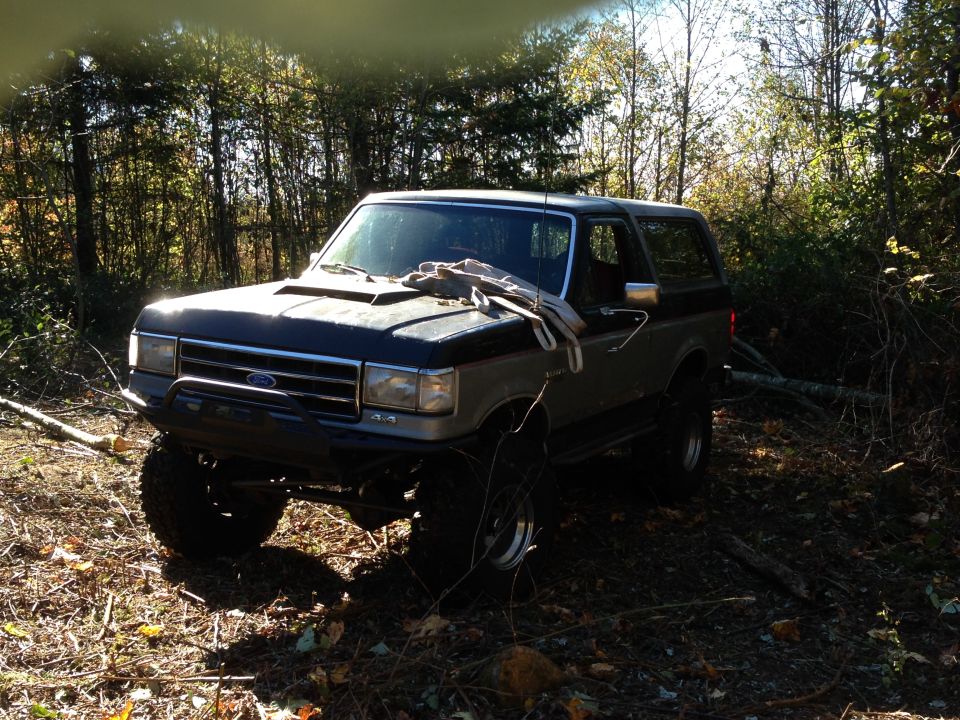 1989 Ford Bronco parked in a wooded area.