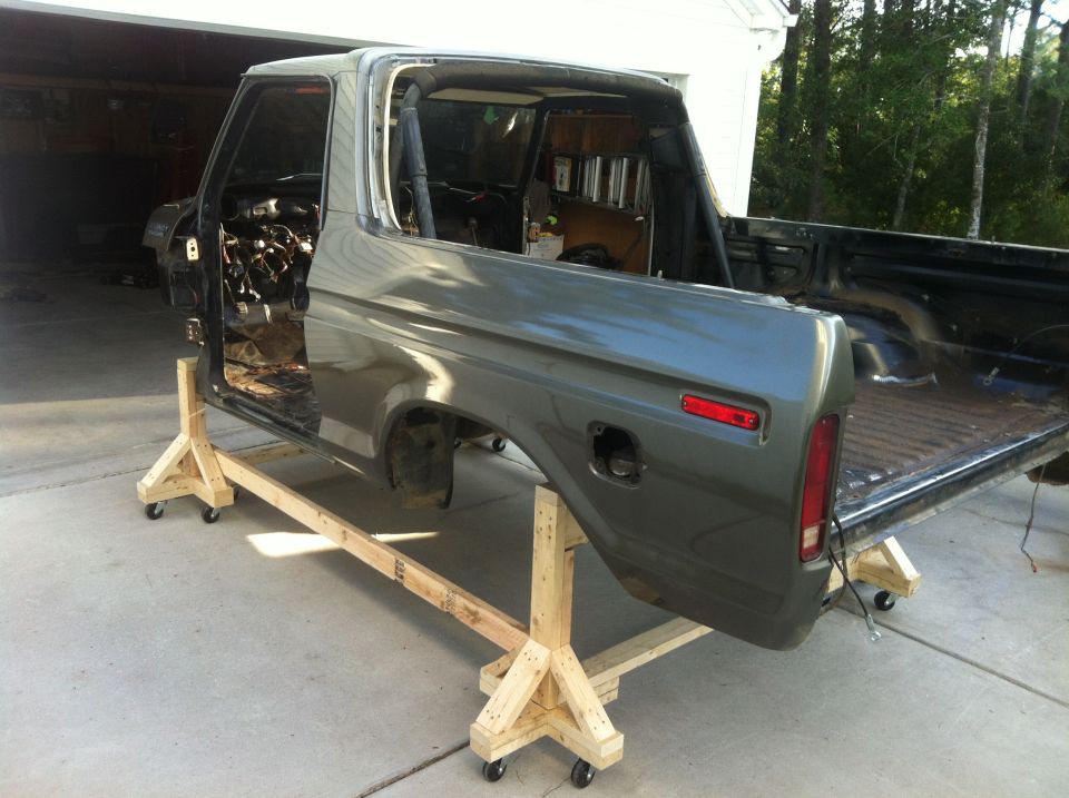 Vintage Ford Bronco body on wooden stands, exterior view.