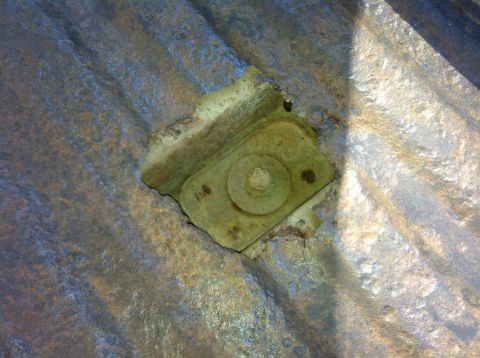 1979 Ford Bronco - A close-up view of a rusted metal surface with a corroded metal bracket and bolt assembly visible in the center. The corrugated texture of…
