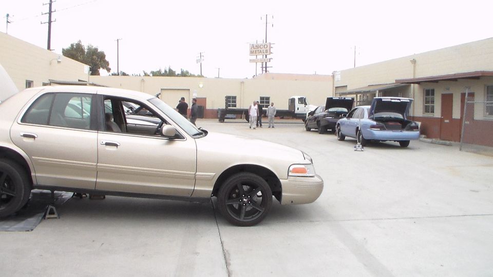 Gold Crown Victoria parked in a lot with other cars behind