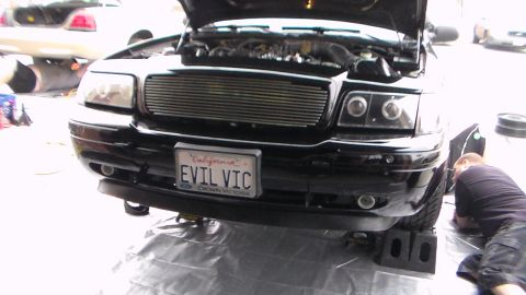 2003 Ford Crown Victoria - Photo of a black Ford Crown Victoria with 'EVIL VIC' plate, billet grille and open hood, not a technical document.