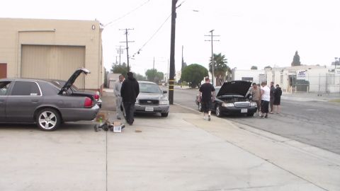 2003 Ford Crown Victoria - Photo of multiple Panther-platform cars parked along a street with people, not a technical document.