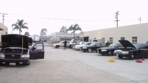 2003 Ford Crown Victoria - Photo of a lineup of cars with hoods open in a shop parking lot, not a technical document.