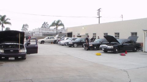 2003 Ford Crown Victoria - Photo of multiple cars with hoods and doors open lined up in a shop lot, not a technical document.
