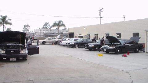 2003 Ford Crown Victoria - Photo of a row of cars with open hoods in a shop parking lot, not a technical document.