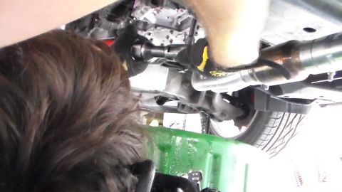 2003 Ford Crown Victoria - Photo of the underside of a vehicle with a person's hand and tools, not a technical document.
