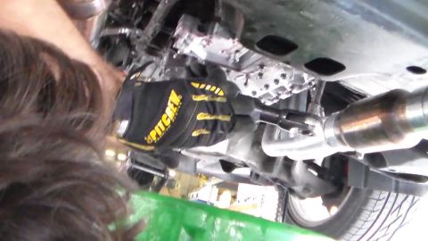 2003 Ford Crown Victoria - Photo of a vehicle underbody with a gloved hand near the driveshaft, not a technical document.