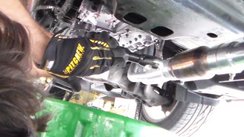 2003 Ford Crown Victoria - Photo of the underside of a car with a gloved hand near suspension and exhaust, not a technical document.