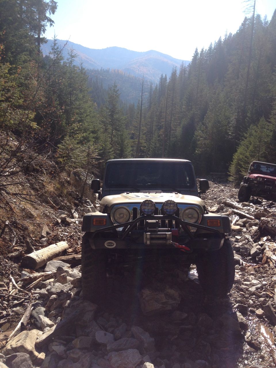 Tan Jeep Wrangler on a rocky mountain trail.