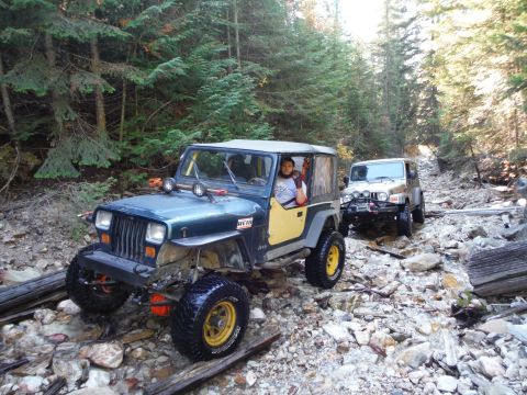 2005 Jeep Wrangler - Two Jeep Wranglers navigate a rough, rocky trail through a forest.