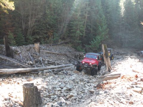 2005 Jeep Wrangler - Two Jeep Wranglers navigate a challenging, rocky terrain in a wooded area.