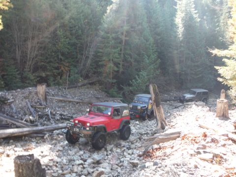 2005 Jeep Wrangler - Multiple Jeeps navigate a rocky, wooded trail.