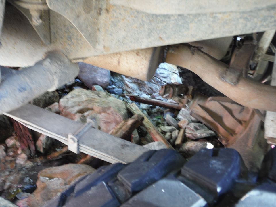 Undercarriage view showing leaf springs, exhaust pipe, and debris