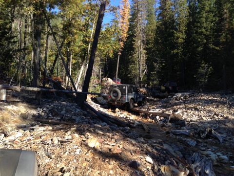 2005 Jeep Wrangler - A silver 2005 Jeep Wrangler drives through a challenging, rocky terrain in a dense forest.