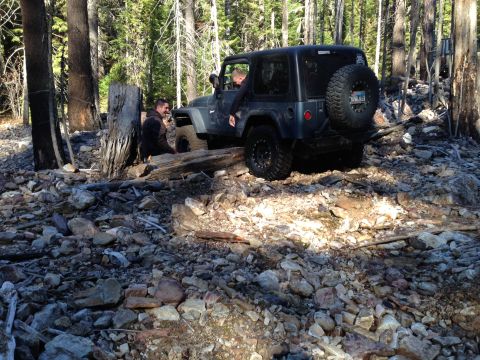 2005 Jeep Wrangler - A Jeep Wrangler is driven over a rocky, wooded trail with two occupants inside.