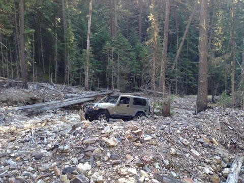 2005 Jeep Wrangler - A tan Jeep Wrangler is parked on a rocky, wooded slope.