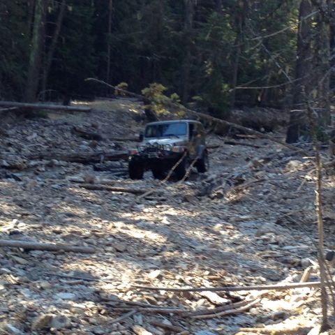 2005 Jeep Wrangler - A silver 2005 Jeep Wrangler navigates a challenging, rocky terrain in a wooded area.