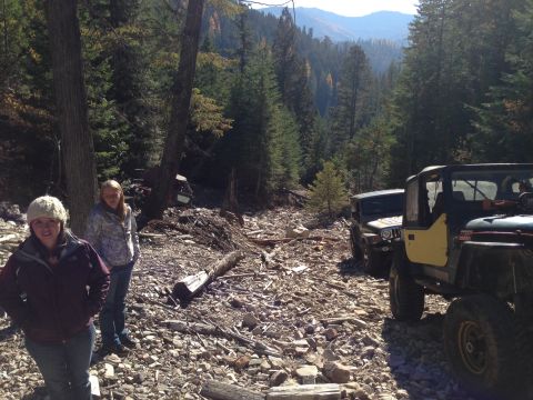 2005 Jeep Wrangler - Two Jeeps are parked on a rough, rocky trail surrounded by trees and mountains.