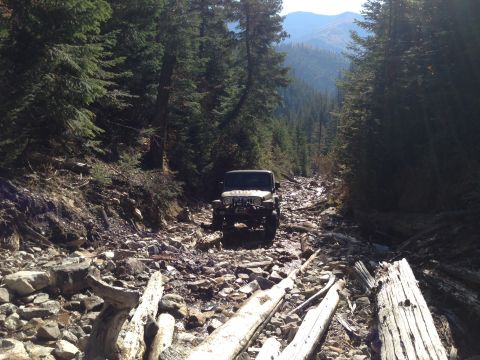 2005 Jeep Wrangler - Jeep Wrangler navigates a challenging rocky path through a dense forest on a mountain.