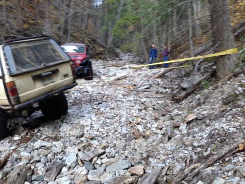 2005 Jeep Wrangler - Two off-road vehicles navigate a challenging rocky path in a wooded area.