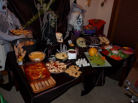 2006 Ford E350 - A table is laden with Halloween-themed food and decorations, including skulls, a skeleton hand, and various party snacks.