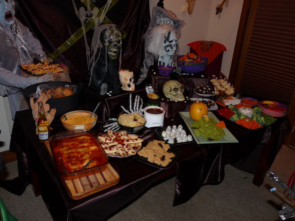 Halloween spread with spooky decorations, dips, snacks, and a beer bottle