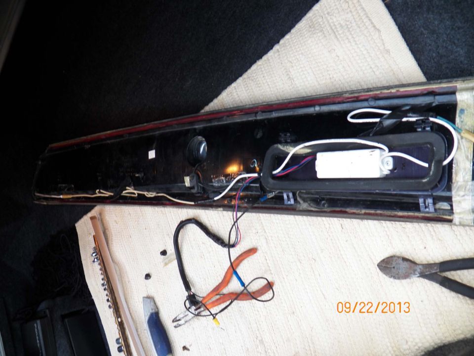 Car tail light assembly with exposed wiring and a ballast. Pliers and a utility knife are nearby