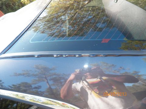 1998 Lincoln Mark VIII - The rear window seal of a dark-colored car is visible, with a reflection of the photographer and a date stamp.