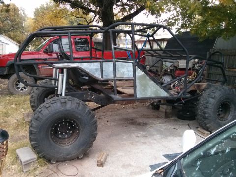 1986 Ford Bronco - A custom-built off-road buggy is shown with a red pickup truck parked behind it.