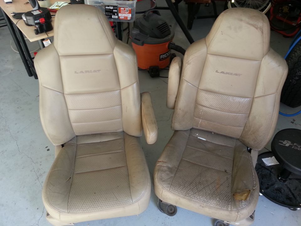 Pair of tan leather Lariat bucket seats, one with torn upholstery