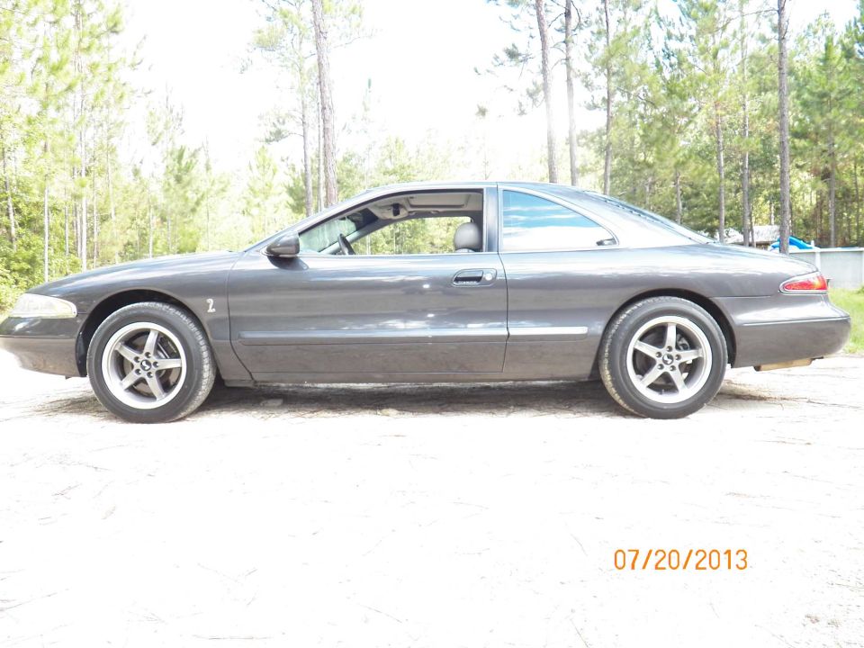 Dark gray coupe with aftermarket wheels parked outdoors